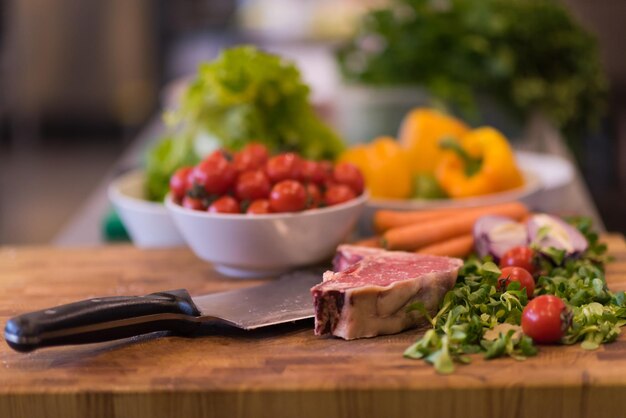Tranche juteuse de steak cru avec des légumes sur une table en bois