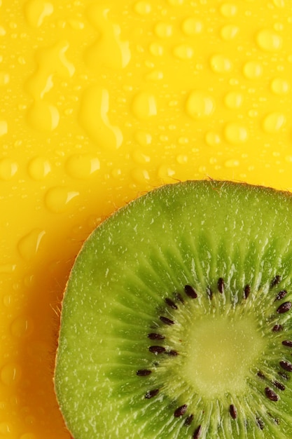 Tranche de kiwi avec goutte sur fond jaune