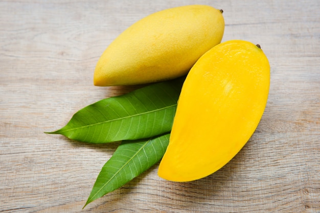 Tranche de mangue et feuilles de mangue d'arbre tropical fruit d'été concept - mangues mûres sucrées coupées en deux