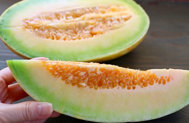 Tranche de melon thaïlandais mûr frais juteux dans les mains de la femme