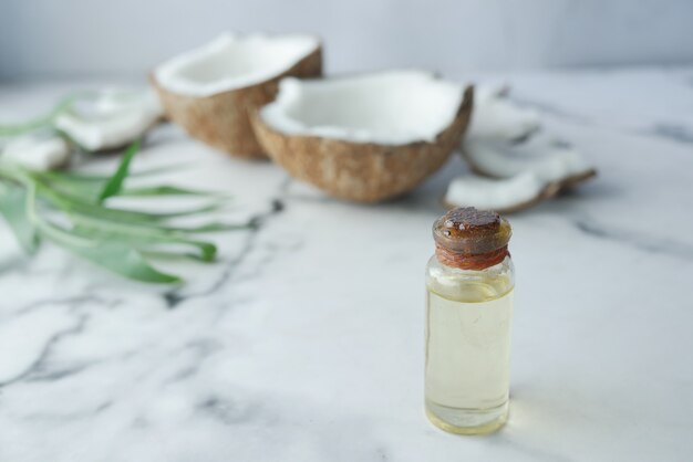 Tranche de noix de coco fraîche et bouteille d'huile sur une table