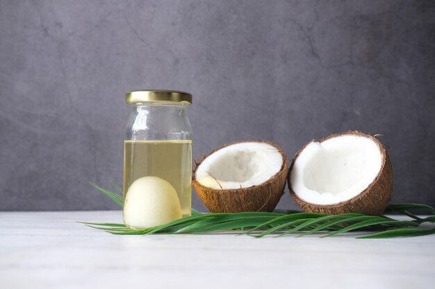 Photo tranche de noix de coco fraîche et bouteille d'huile sur une table