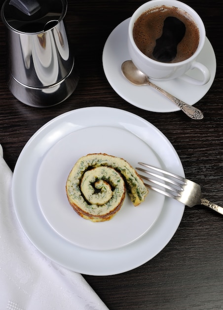 Tranche d'omelette aux herbes et une tasse de café noir sur la table