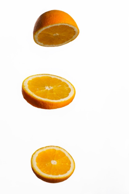 Une tranche d'orange flotte dans l'air sur un fond blanc