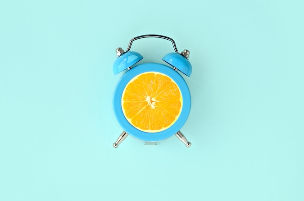 Tranche d&#39;orange fraîche dans un petit réveil bleu