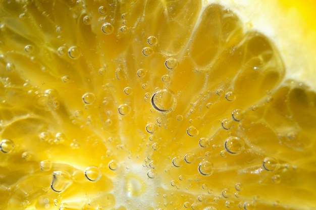 Une tranche d'orange recouverte de bulles se trouve dans un verre d'eau gazeuse. Fermer.