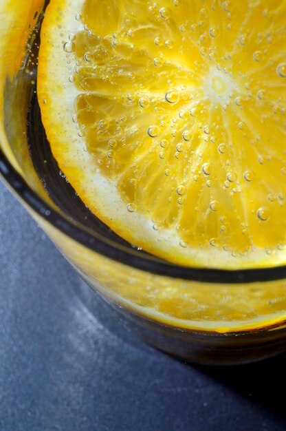 Photo une tranche d'orange recouverte de bulles se trouve dans un verre d'eau gazeuse. fermer.