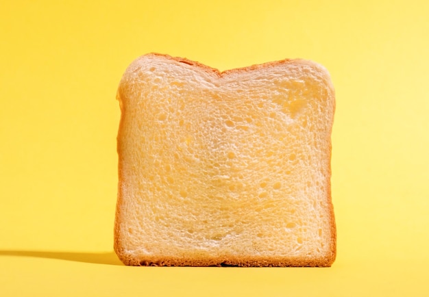 Une tranche de pain blanc isolée sur un fond jaune