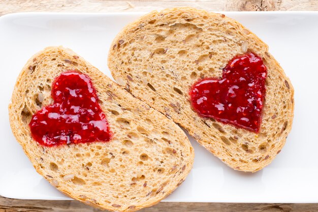 Tranche de pain de grain avec forme de coeur de confiture.