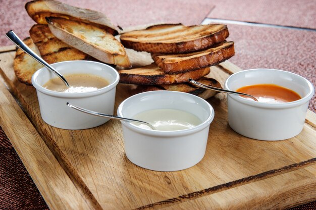 Tranche de pain grillé rôti pané avec du fromage et du sésame glissé dans une sauce sur une planche de bois