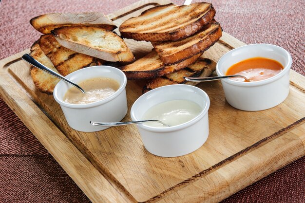 Tranche de pain grillé rôtie en panée au fromage et au sésame glissée dans une sauce sur une planche de bois