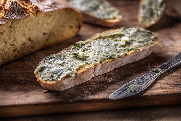 Tranche de pain maison fraîchement cuit avec une généreuse couverture de beurre aux herbes sur le dessus