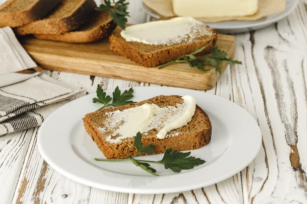 Tranche de pain de seigle beurré sur table en bois