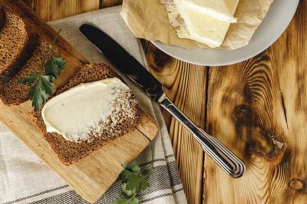 Photo tranche de pain de seigle beurré sur table en bois