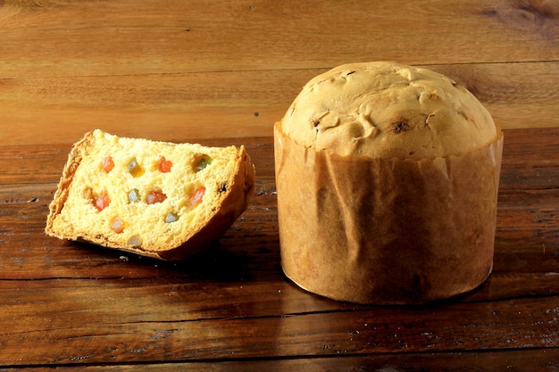 Tranche de Panettone agrandi avec table en bois de fruits confits. Décoration de Noël. avant v