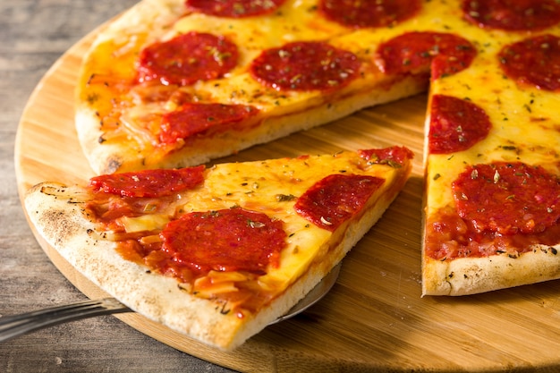 Tranche de pizza au pepperoni italien chaud sur table en bois.