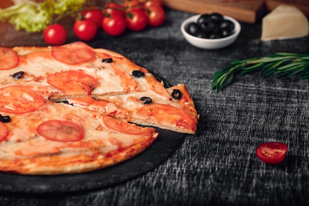 Tranche de pizza avec du fromage, de la truite, des tomates, des olives et des crevettes au tableau.