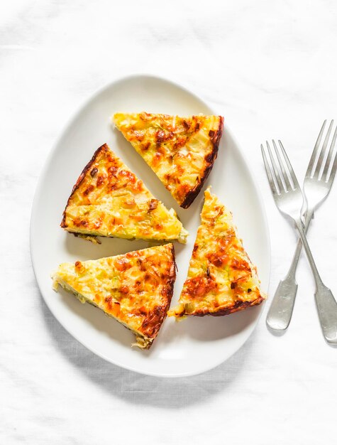 Tranche de poireaux pommes de terre tortilla de courgettes sur fond clair vue de dessus