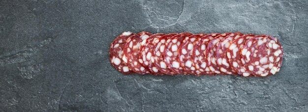 Photo tranche de salami de saucisse fumée isolée sur fond sombre avec chemin de détourage et pleine profondeur de champ