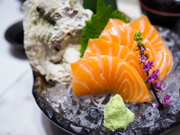 Tranche de saumon cru ou sashimi de saumon de style japonais frais servi sur de la glace avec du wasabi frais