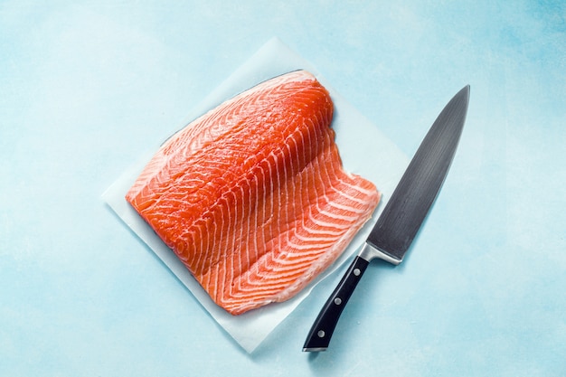 Photo tranche de saumon frais sur une planche à découper en bois avec un couteau de chef sur la table. recette de cuisine. fond de nourriture. produits de poisson frais