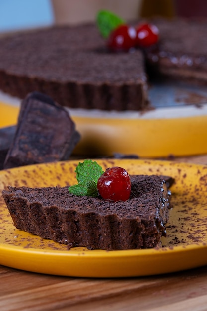 une tranche de tarte au chocolat noir sur une assiette jaune