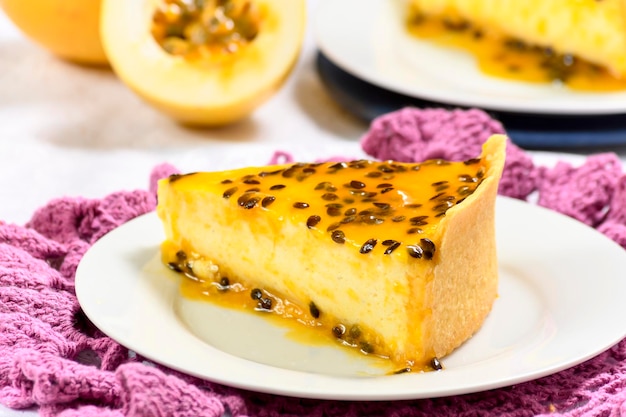 TRANCHE DE TARTE AUX FRUITS DE LA PASSION SUR UNE ASSIETTE BLANCHE PHOTOGRAPHIÉE EN GROS PLAN AVEC MISE AU POINT SÉLECTIVE