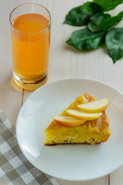 Une tranche de tarte aux pommes avec un verre de jus de pomme