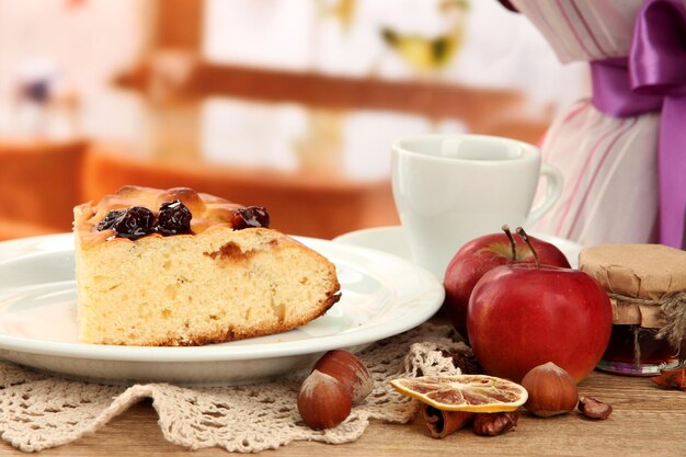 Tranche de tarte maison savoureuse avec de la confiture et des pommes sur une table en bois au café