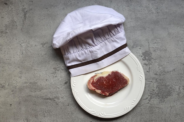 Une tranche de viande de boeuf crue avec on white plate