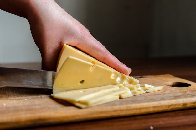 Trancher le fromage sur une planche de bois.