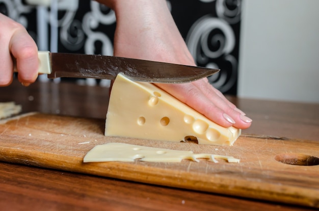 Trancher le fromage sur une planche de bois.