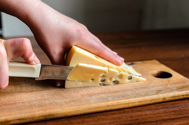 Trancher le fromage sur une planche de bois.