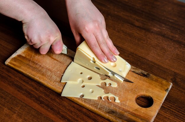 Trancher le fromage sur une planche de bois.