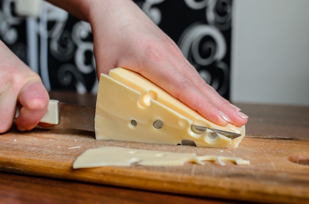 Trancher le fromage sur une planche de bois.