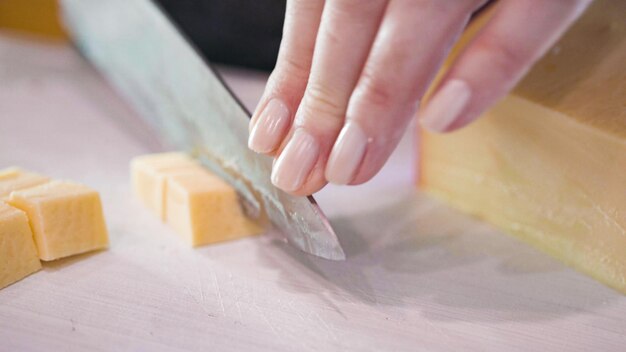 Trancher le gouda en petits cubes sur une planche à découper blanche.