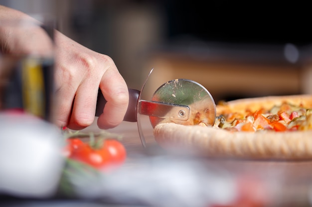 Trancher la pizza fraîche avec un couteau à rouleau