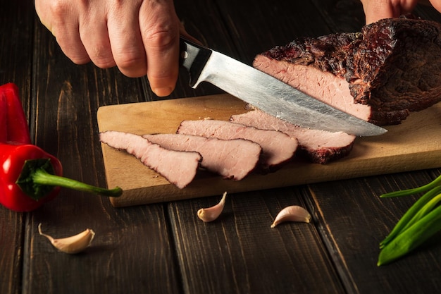 Trancher la viande de boeuf cuite au four avant de préparer le dîner par les mains du chef