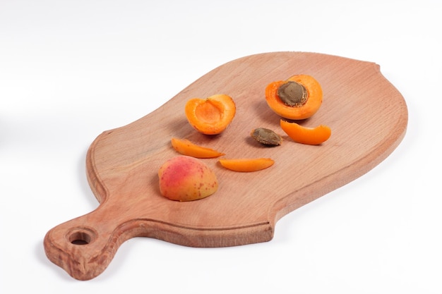 Tranches d'abricots sur planche de bois isolé sur fond blanc Concept d'aliments biologiques Gros plan