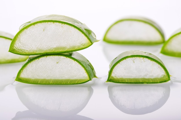 Tranches d'aloe vera frais sur une surface blanche avec réflexion