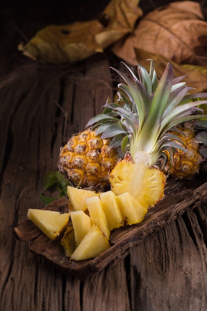 Photo tranches d'ananas et d'ananas décortiqués style asiatique sur le vieux fond en bois.