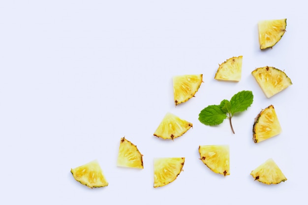 Tranches d'ananas frais avec des feuilles de menthe sur fond blanc.