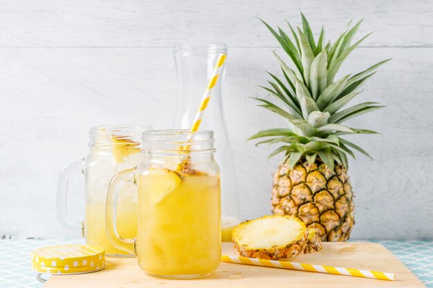 Tranches d&#39;ananas et de jus dans la verrerie sur la table en bois