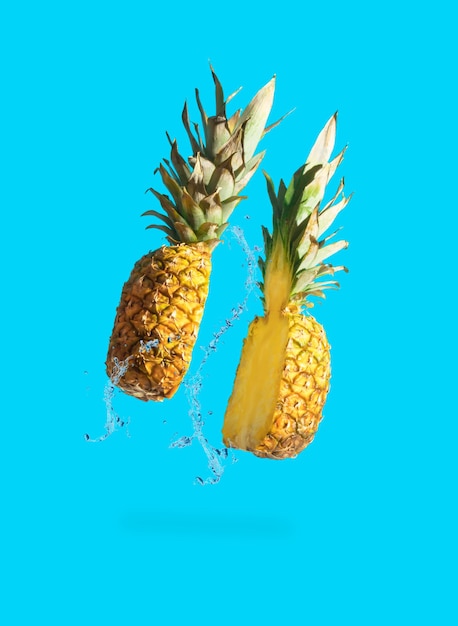 Tranches d'ananas juteux avec des éclaboussures d'eau sur fond bleu pastel Concept de fruits minimal Idée alimentaire