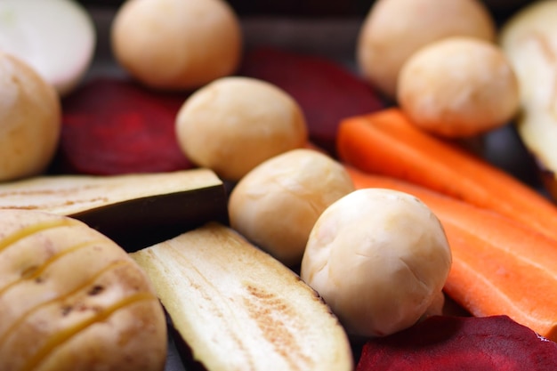 Tranches d'aubergines betteraves carottes oignons pommes de terre et champignons entiers sur papier parchemin avant la cuisson des aliments sains libre