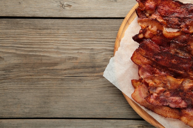Tranches de bacon frites sur une planche à découper. Vue de dessus