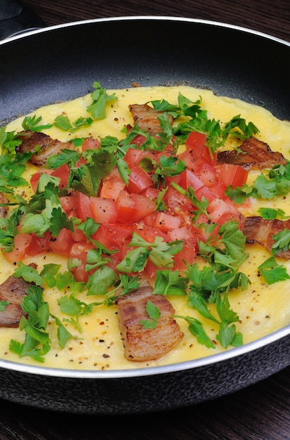 Tranches de bacon d'omelette, tomates aux herbes dans une poêle