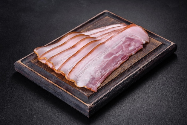 Tranches de bacon sur une planche à découper en bois Viande de porc