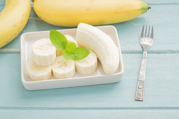 Tranches de banane sur un bol sur un fond bleu en bois.