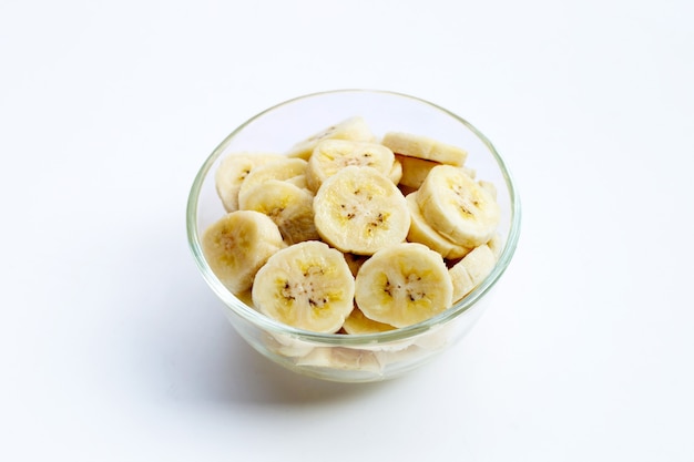 Tranches de banane dans un bol en verre sur fond blanc.